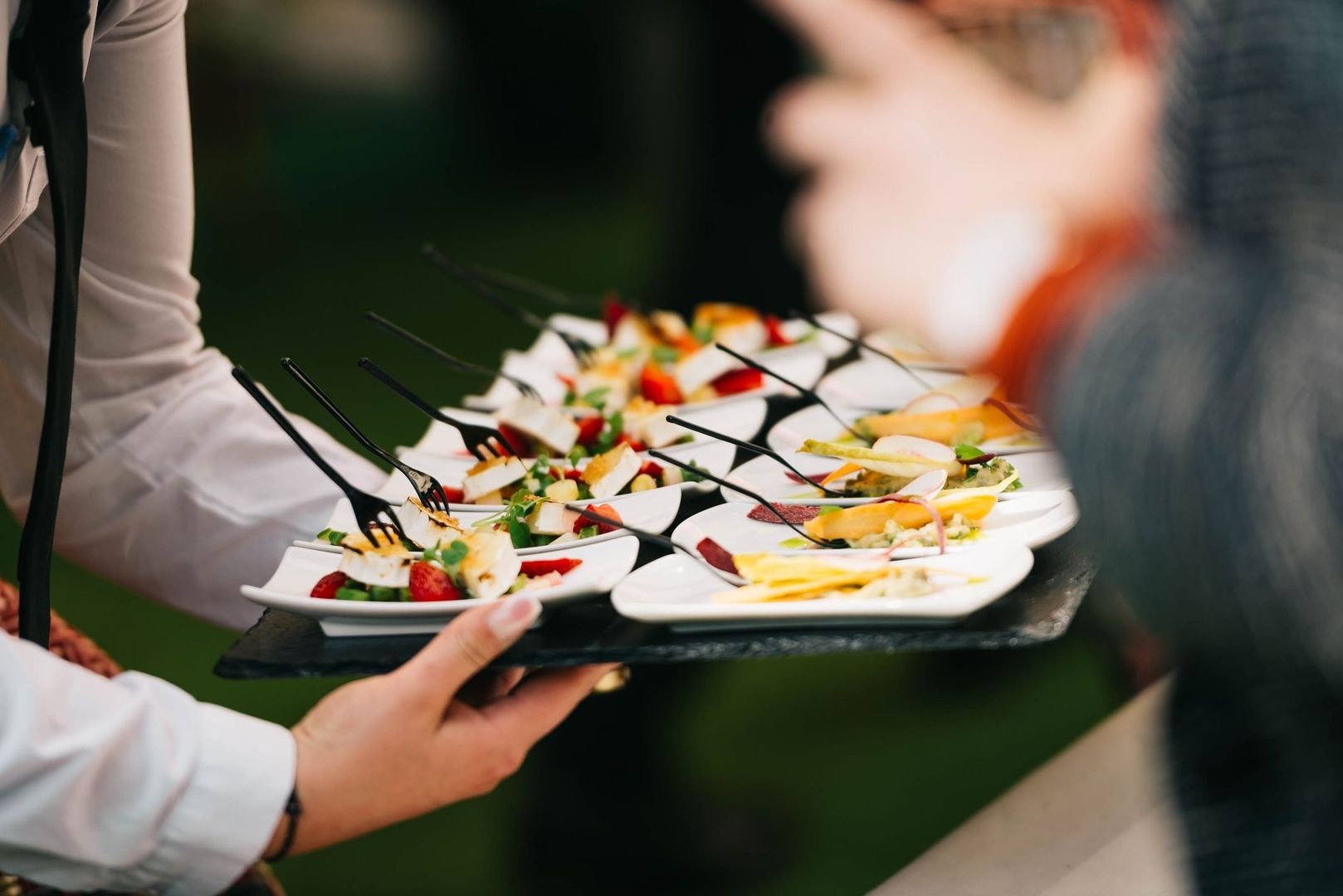 Serveringsbricka med små bufférätter och mingelmat på vita tallrikar